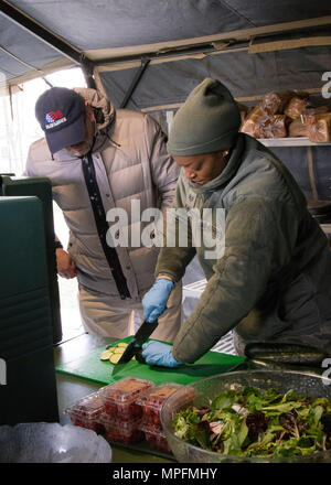 David Richmond, Vertreter der National Restaurant Association, Uhren Staff Sgt. Mercedes Mc Coy-Garrett, Food Services Specialist, Memorial Angelegenheiten 512th Squadron, hacken Sie eine Zucchini nach Vermittlung der richtigen Schnitttechniken, während für das Jahr 2017 John L. Hennessy Award in Dover Air Force Base, Del, 3. März 2017 zu konkurrieren. Die hennessy Auszeichnung würdigt hervorragende Leistung bei foodservices über mehrere militärische Niederlassungen. (U.S. Air Force Foto/Renee M.Jackson) Stockfoto