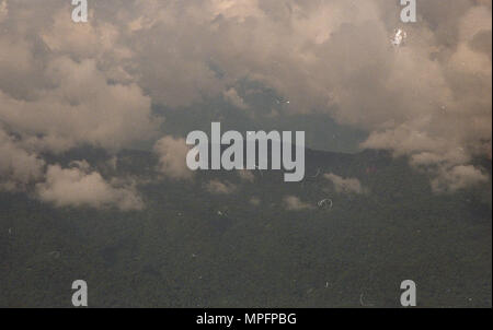 Dieses Bild zeigt eine bergige Landschaft, die mit verstreuten Wolken bedeckt ist und das natürliche Gelände und die Höhenänderungen hervorhebt. Das Foto zeigt Gipfel, Grate und Täler und veranschaulicht die Geographie der Region. Wolkenformationen zeigen Wettermuster und atmosphärische Bedingungen über den Bergen an. Die Szene betont topografische Merkmale, natürliche Vegetation und den Kontrast zwischen Sonnenlicht und Schatten in der rauen Umgebung und bietet einen Überblick über Landformen und Klimaeinflüsse. Stockfoto