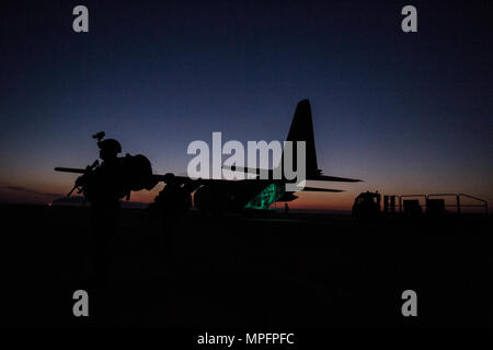 Ein 379 Expeditionary Sicherheitskräfte Squadron Fly Away Mitglied des Sicherheitsteams, sichert der Bereich um eine C-130 Hercules, während der Ladung, bei der Unterstützung einer Combined Joint Task Force - inhärenten Lösung Mission 7 März 2017 entladen wird. Die 746Th EAS bietet globalen strategischen Lufttransport, airdrop, aeromedical Evacuation und humanitäre Hilfe für Personal, Ausrüstung und Vorräte im gesamten US Central Command. (U.S. Air Force Foto: Staff Sgt. Matthew B. Fredericks) Stockfoto