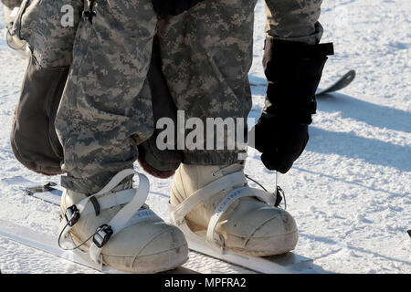 Ein Wettbewerber Riemen auf seiner skiis Für die Teilnahme an der US-Armee Alaska Winter Spiele am Fort Wainwright, Alaska, 9. März 2017 fertig zu werden. Veranstaltungen in diesem Jahr gehören Downhill Ski Racing, live-fire biathlon Range, Stress schießen, land Navigation, Skijöring, Einrichten der Arktis 10-Mann Zelt und Herd richtig, und die Bewertung und Behandlung von einem Unfall in der extremen Kälte. Als Amerika's Arctic Krieger und Experten der US-Armee in Überlebenden, Betrieb, kämpfen und gewinnen in extrem kalten Wetter und Höhenlage Umgebungen, alle Fertigkeiten, die während der Spiele getestet sind kritisch für alle USARA Stockfoto