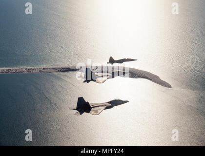 Ein paar F-22 Raptors mit der 95Th Fighter Squadron und ein T-38 Talon mit der 2 Fighter Training Squadron, Tyndall Air Force Base, Fla., fliegen in Formation entlang der "Vergessenen Küste" der Florida Panhandle, wie sie nach Durchführung von Schulungen über den Golf von Mexiko, 9. März 2017. 2. stellt FTS routinemäßig die 95th FS mit Luft-zu-Luft-Bedrohung der Replikation in Unterstützung des F-22 bekämpfen und formale Ausbildung. (U.s. Air Force Foto von Master Sgt. Burt Traynor/Freigegeben) Stockfoto