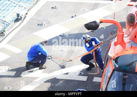 Den Boden aircrew auf der Coast Guard Cutter Spencer sichert den Helikopter in das Flight Deck am Mittwoch, März 8, 2017. In Boston Homeported, der Spencer ist eine 270-Fuß-medium endurance Cutter mit einer Mannschaft von 15 Beamten ergänzen und 74 Mannschaften. (U.S. Coast Guard Foto von Petty Officer 2nd class Timothy Midas) Stockfoto