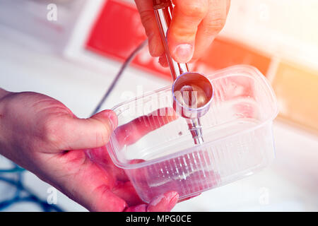 Nahaufnahme einer Künstlerin in Jeans reinigt und bereitet die Airbrush für die Arbeit der Anstrich der Wände. Stockfoto