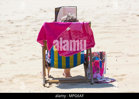 Bournemouth, Dorset, Großbritannien. 23. Mai 2018. UK Wetter: herrlich warmen sonnigen Tag mit ungebrochenen Sonnenschein, die Besucher des Beach Head. Frau liest Buch im Liegestuhl - von hinten. Credit: Carolyn Jenkins/Alamy leben Nachrichten Stockfoto