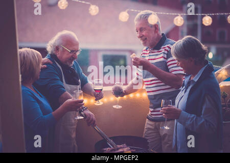 Grill BBQ und etwas Wein ein Ereignis zu feiern. Gruppe erwachsener Menschen genießen Sie Lebensstil im Freien auf der Terrasse mit Blick auf die Stadt Essen Essen und Wein zu trinken. Stockfoto