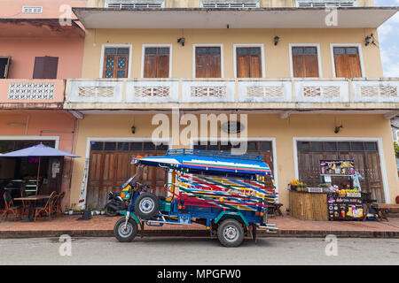 Farbenfrohe Dreirad Taxi Jumbo (oder Tuk Tuk) vor einem alten französischen Kolonialzeit Gebäude auf der Kingkitsarath Straße in Luang Prabang, Laos genannt Stockfoto