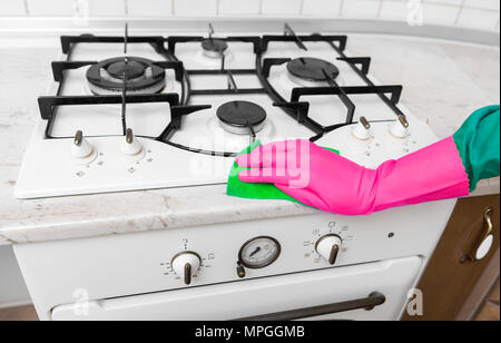 Hand in Gummihandschuhe reinigt eine Küche Gasherd. Stockfoto