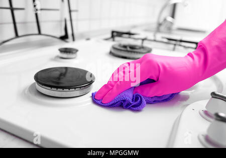 Hand in Gummihandschuhe reinigt eine Küche Gasherd. Stockfoto