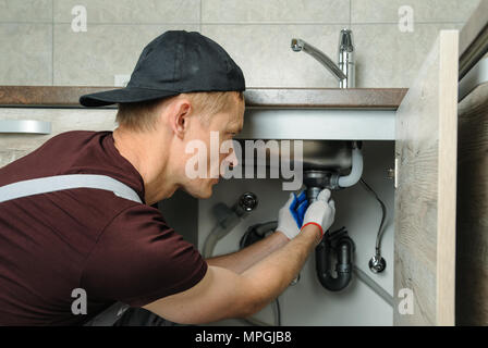 Arbeitnehmer setzt Falle für die Küchenspüle. Stockfoto