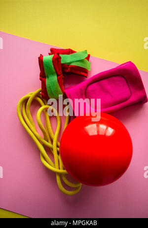 Rot Gymnastikball, Knieschoner, Gewichtungen und Springseil auf einem rosa Hintergrund. Sport, Hobby und Lifestyle Konzept. Top ansehen und kopieren. Stockfoto
