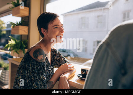 Attraktive junge Frau lächelt und spricht mit ihrem Mann im Restaurant. Frau, eine tolle Zeit mit ihrem Freund im Coffeeshop. Stockfoto