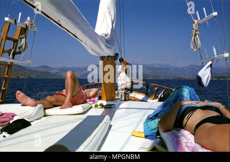 Ein junger Mann und eine Frau in den frühen 30er Jahren zum Sonnenbaden an den Bug eines gulet Boot, auf einer gulet Kreuzfahrt rund um das Mittelmeer Küste der südlichen Türkei. Stockfoto