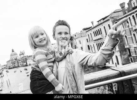 Baby Mädchen und Mutter deutete beim stehen auf der Brücke mit Blick auf Canale Grande in Venedig, Italien Stockfoto