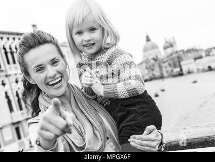 Baby Mädchen und Mutter deutete in der Kamera beim stehen auf der Brücke mit Blick auf Canale Grande in Venedig, Italien Stockfoto