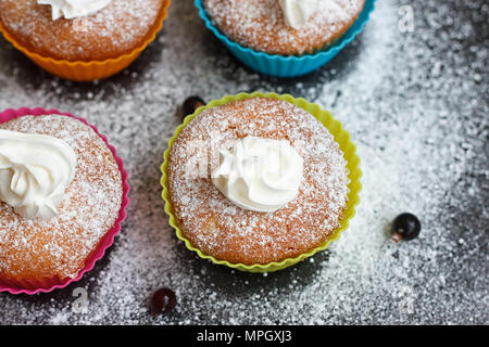 Muffins in bunten Silikon Formen mit Schlagsahne Stockfoto