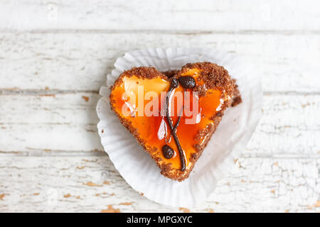 Kaffee Kuchen in der Form eines Herzens auf einem weißen Holz- Hintergrund Stockfoto