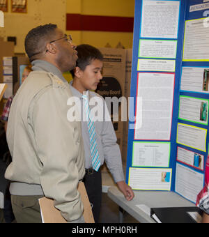 (Links) Oberst Sekou Karega, kommandierender Offizier, Marine Corps Logistikstandort Barstow, Calif.; Gespräche mit Jamie Martinez, 13, Student aus Barstow Stammzellen Akademie, über seine Barstow Unified School District Science Fair-Projekt "Sammeln von Flüssiges Gold." Das Experiment beteiligt die Wiederverwendung von plastikflaschen Regenwasser zu speichern und die Anzahl der Kunststoff in die Umwelt freigesetzt werden, reduzieren. Mehrere andere Marinen aus MCLBB fungierte auch als Richter in der Messe, einer Tradition, die einige Jahre. Veranstalter der BUSD Science Fair sagten, sie haben die größte Anzahl der Einträge für die Veranstaltung in der Messe hist Stockfoto