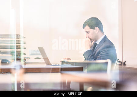 Porträt der erfolgreiche Geschäftsmann in hellen, modernen Büro Arbeiten am Laptop. Business und Entrepreneurship Konzept. Stockfoto
