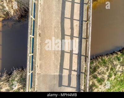 Luftaufnahme aus geringer Höhe von 10 Metern von einer kleinen Brücke über einem dunklen Stream, mit Drone Stockfoto