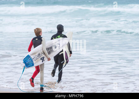 Die jungen Surfer, die ihre Surfbretter in das Meer bei Fistral Beach in Newquay Cornwall. Stockfoto