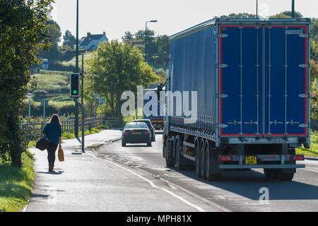 Eine Frau geht auf dem Gehsteig neben Fahrzeugen entlang der Arundel bypass Reisen, auf der A27 unterwegs, in Arundel, West Sussex, UK. Stockfoto