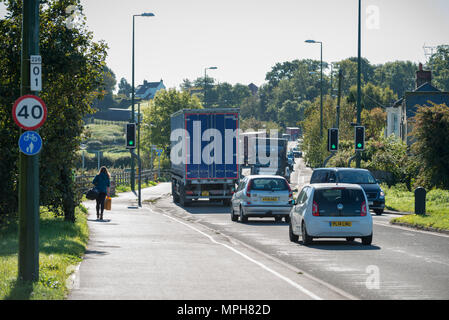 Eine Frau geht auf dem Gehsteig neben Fahrzeugen entlang der Arundel bypass Reisen, auf der A27 unterwegs, in Arundel, West Sussex, UK. Stockfoto