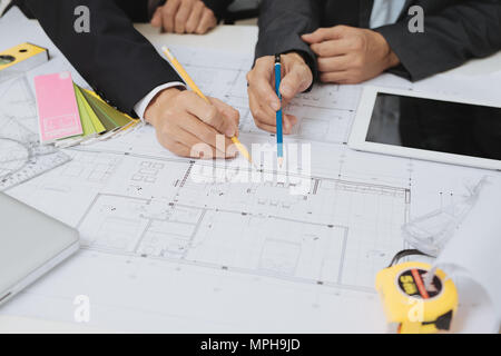 Architekten und Techniker diskutieren auf dem Schreibtisch mit Bauplan und Bau Werkzeuge Stockfoto