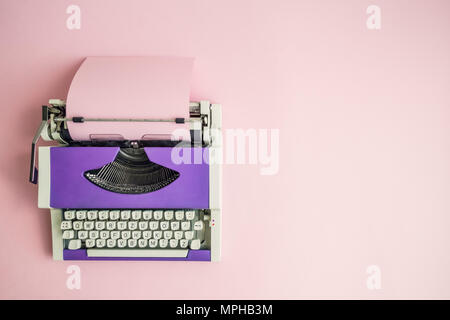 Blick von oben auf die violett vintage Schreibmaschine mit leeren Blatt Papier auf dem Tisch. Platz für Kopieren. Stockfoto