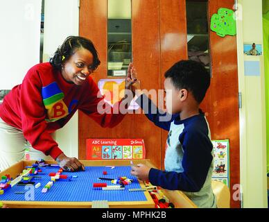 Fort Lee Child Development Center Anbieter Dannetter Braun, ein Kinder- und Jugendprogramm Assistant, gibt eine fünf bis Kaiden Hilliard für eine gute Wahl zu einem Anteil auf ein Spielzeug zum 13. März in Yorktown CDC Starke Anfänge Klassenzimmer. Stockfoto