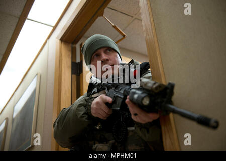 Air Force Staff Sgt. Nicholas Woolridge, ein streifenpolizist mit der 673 d Security Forces Squadron Uhren der Flur als seine Mitarbeiter löscht den nächsten Raum in der 773Rd Bauingenieur Squadron, März 13. Die Sicherheitskräfte Geschwader auf gemeinsamer Basis Elmendorf-Richardson führt regelmäßig keine - Bekanntmachung der Tests der aktiven shooter Mentalitäten Büros' um. (U.S. Air Force Foto von älteren Flieger Kyle Johnson) Stockfoto