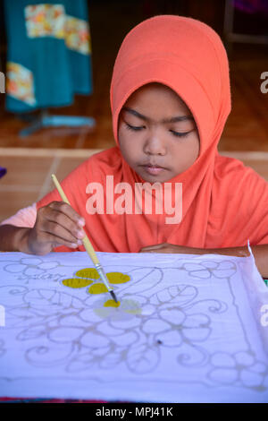 Krabi, Thailand - 2. Mai 2015: Cute muslimische Mädchen mit rosa hijab Malerei Muster auf Batikstoffen in Ihrem Haus in Krabi, Thailand Stockfoto