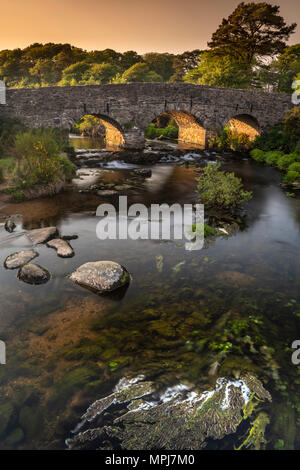 An einem warmen Sommerabend, nach den Touristen abreisen, die East Dart River rieselt unter der schöne Granit gebaute Brücke bei Postbridge in Dartmoor Stockfoto