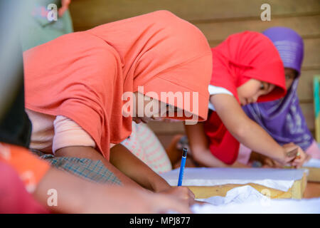 Krabi, Thailand - 2. Mai 2015: Cute muslimische Mädchen zeichnen Muster auf Batikstoffen für Malerei in Ihrem Haus in Krabi, Thailand Stockfoto