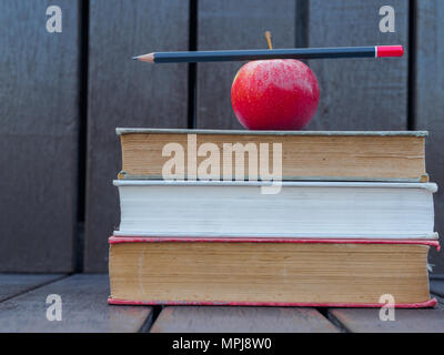 Bleistift auf roten Apfel auf Stapel alte Bücher Stockfoto