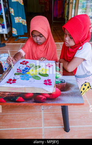 Krabi, Thailand - 2. Mai 2015: Cute muslimische Mädchen mit rosa hijab Malerei Muster auf Batikstoffen in Ihrem Haus in Krabi, Thailand Stockfoto