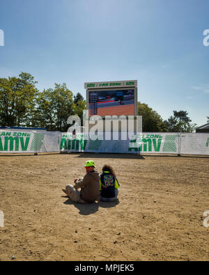 19./20. Mai 2018. Le Mans, Frankreich. Hinter die Kulissen der MotoGP. Ein junges Paar sitzen auf dem Boden Schmutz den Trainings zu beobachten Auf einer der großen Leinwände. Stockfoto