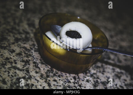 Schwarzer Sesam mochi Kugeln in Metalllöffel, Sesam Knödel Suppe in transparentem Glas Schüssel auf dem Klapptisch, Vintage getönt Stockfoto