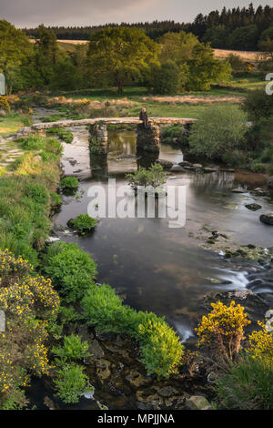 An einem warmen Sommerabend, nach den Touristen abreisen, die East Dart River rieselt unter dem wunderschönen Granit Postbridge Clapper Bridge an in Stockfoto