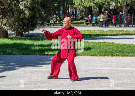 Ein Kampfkünstler trägt eine rote Kung Fu oder Tai Chi einheitliche Üben von Tai Chi im Park in Peking, China Stockfoto