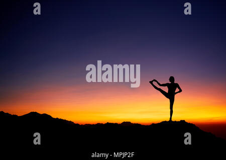 Passen Mann in silhouette Yoga balance Pose am schönen orange Sonnenuntergang Himmel Hintergrund Stockfoto