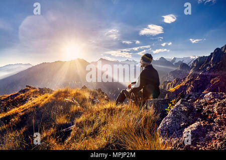 Touristische in Nepali Hut sitzen auf dem Hügel und suchen bei Sonnenaufgang in den Bergen Stockfoto