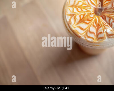 Close-up Iced Caramel Macchiato mit braunen Stroh in mit nach Hause nehmen, Kunststoff, Glas auf Holz- Hintergrund Stockfoto