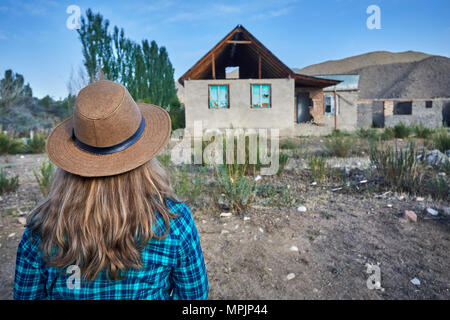 Frau mit Hut und kariertes Hemd auf ruiniert altes Haus im Dorf Stockfoto