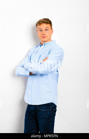 Junger Mann gegen die Wand mit gekreuzten Armen stehen. Stockfoto