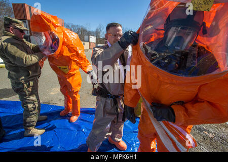 21 New Jersey National Guard Massenvernichtungswaffen Destruction-Civil Support Team Mitglieder 2. Lt Brandon Botley, Links, unterstützt Strike Team Mitglied Sgt. Joe Bercovic, zweiter von links, während Staff Sgt. Kenneth Williams, zweiter von rechts, zips Strike Team Mitglied Staff Sgt. Nicky Lams Ebene ein Schutzanzug während einer Übung mit dem Picatinny Arsenal Feuerwehr am New Jersey Homeland Defense Homeland Security Center am Picatinny Arsenal, N. J., März 23, 2017. Das 21 WMD-CST ist eine gemeinsame Einheit aus New Jersey National Guard Soldaten und Piloten, deren Aufgabe es ist, zu unterstützen. Stockfoto