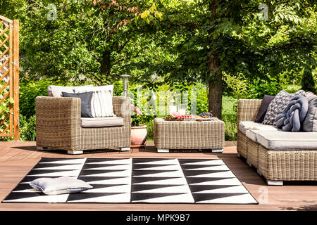 Bequeme Gartenmöbel und geometrische Wolldecke auf einer Terrasse in Spa Resort Stockfoto