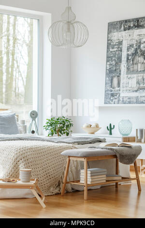 Helles Schlafzimmer mit einem großen Bett und einem Schrank mit Ornamenten daneben Stockfoto