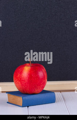 Red Apple auf alten mini Buch gegen Tafel mit Platz für Text. Schule Konzept Stockfoto