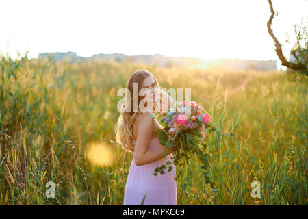 Schwangere Junge kaukasier Frau Rosa Kleid mit Blumenstrauß in Steppen Hintergrund stehen. Stockfoto