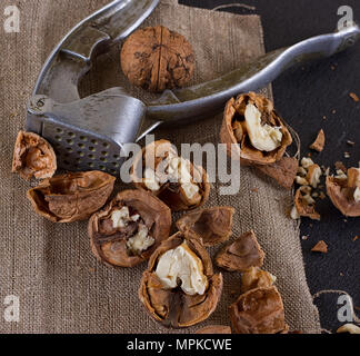 Walnüsse und einen Nussknacker auf eine Tabelle mit Sackleinen abgedeckt Stockfoto